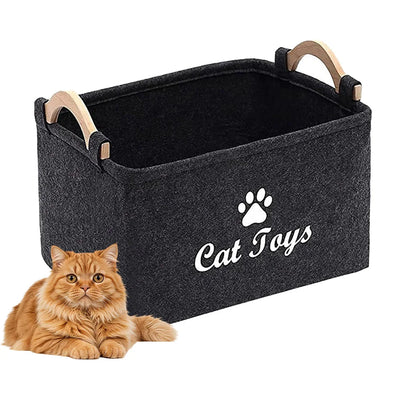Aviour black felt pet accessories storage basket with wooden handles and Cat Toys label beside a ginger cat